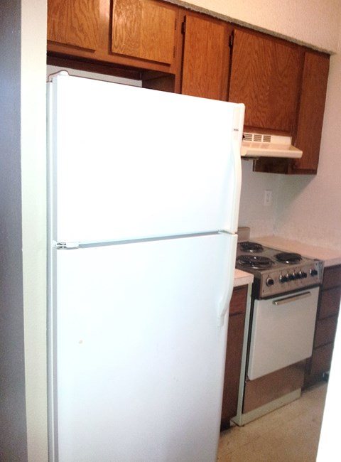 A white refrigerator is in a kitchen next to a stove.