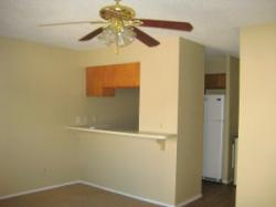 A room with a ceiling fan and a white refrigerator.