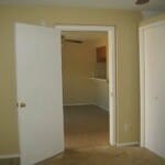 A white door is open to a room with a carpeted floor.