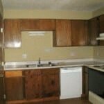 an empty kitchen with wooden cabinets and a white dishwasher