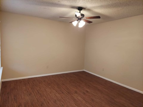 Empty room with a ceiling fan and wooden flooring.