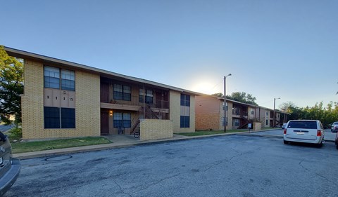 A parking lot in front of a building with a white van parked.