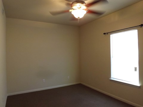 A room with a ceiling fan and a window.