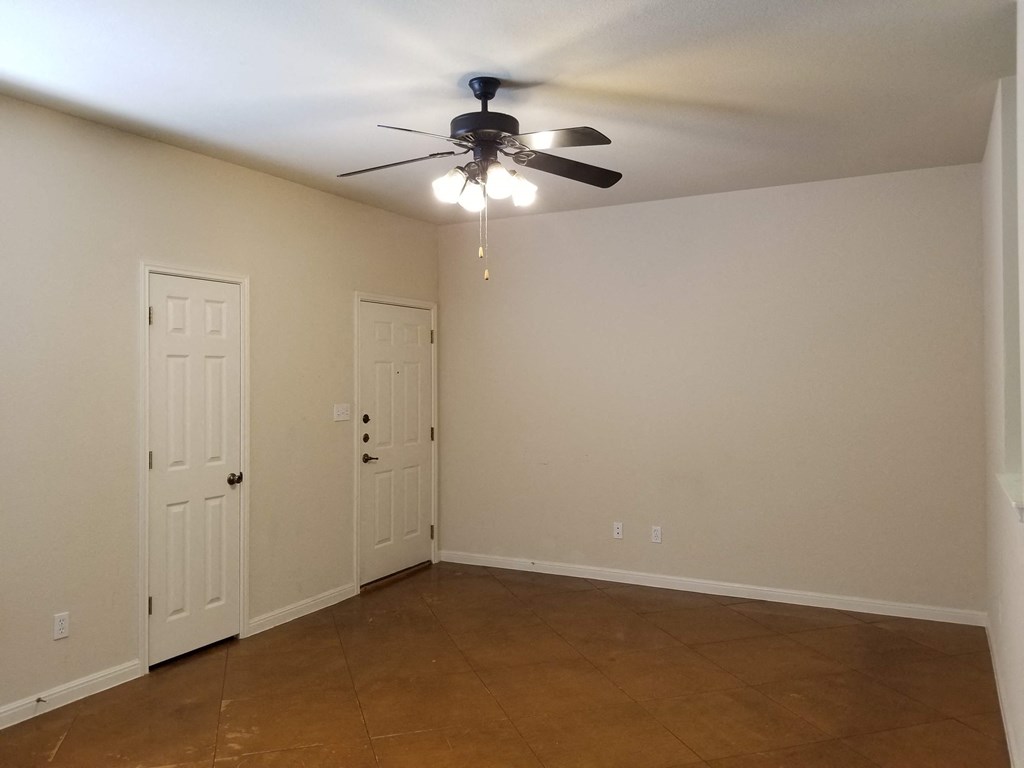 a empty living room with a ceiling fan and a door