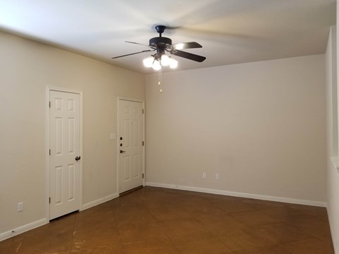 A room with a ceiling fan and two doors.