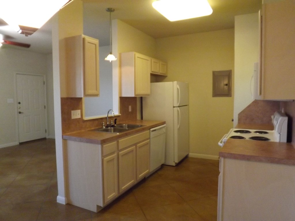 an empty kitchen with a refrigerator and a sink