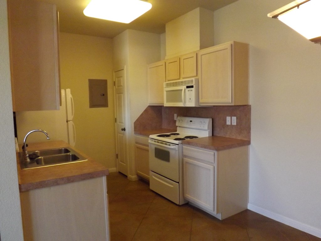 an empty kitchen with white appliances and a sink
