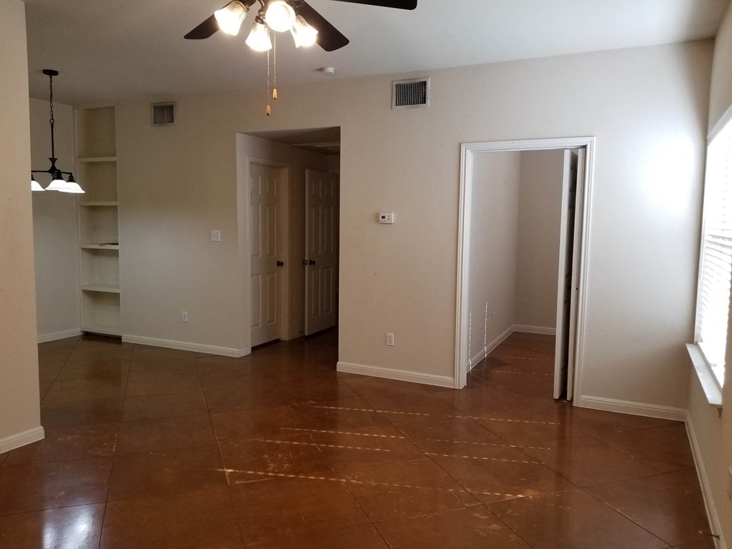 an empty living room with a closet and a ceiling fan