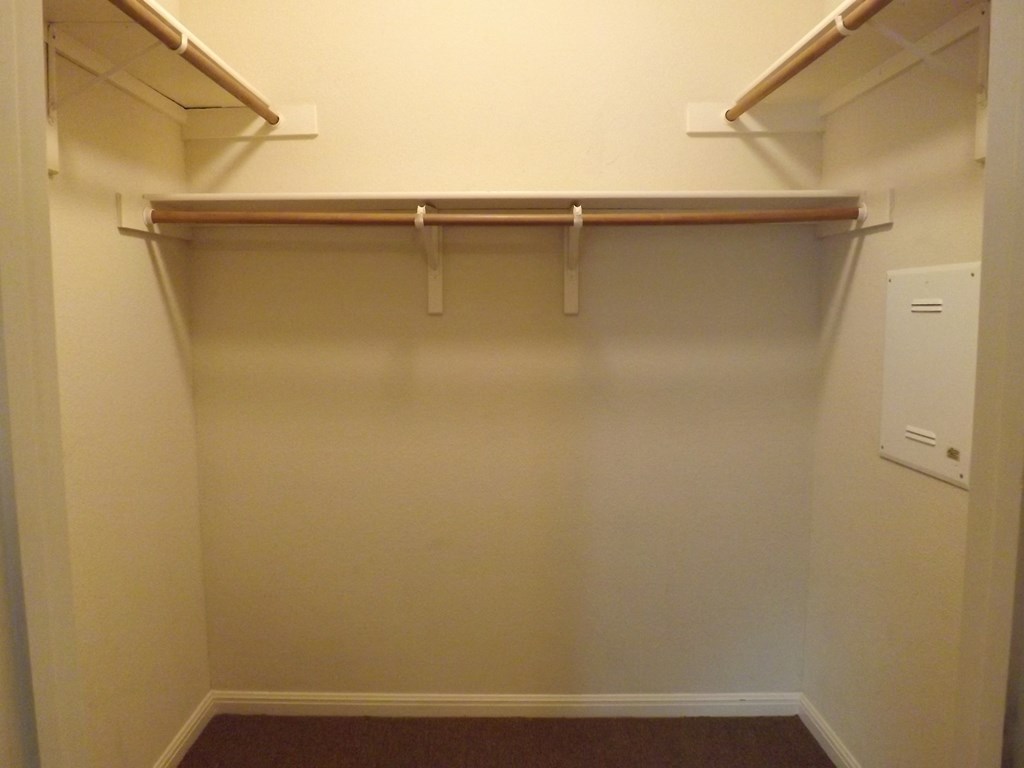 a walk in closet in an empty room with a white wall and a white wardrobe