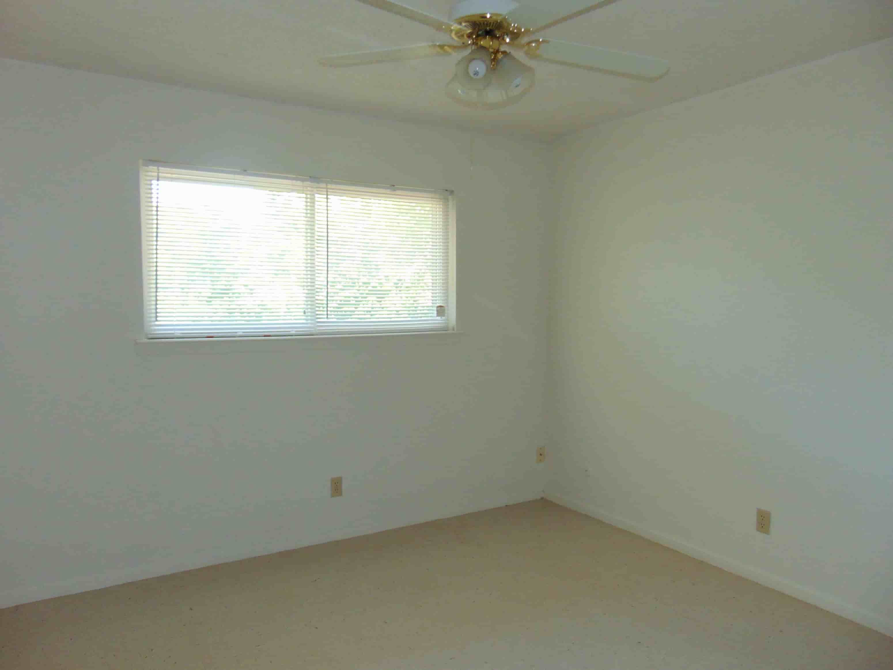 an empty room with a ceiling fan and a window