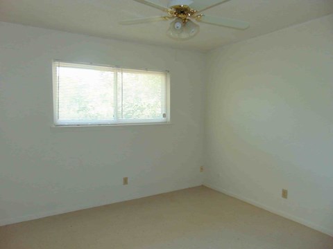 an empty room with a ceiling fan and a window