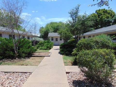 A pathway leads to a white building in a residential area.