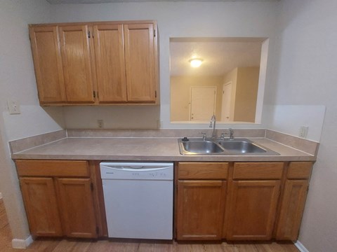 A kitchen with wooden cabinets and a white dishwasher.