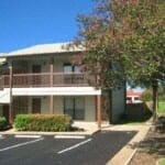 A two story building with a parking lot in front.