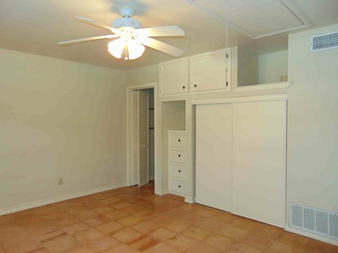 a bedroom with white cabinets and a ceiling fan
