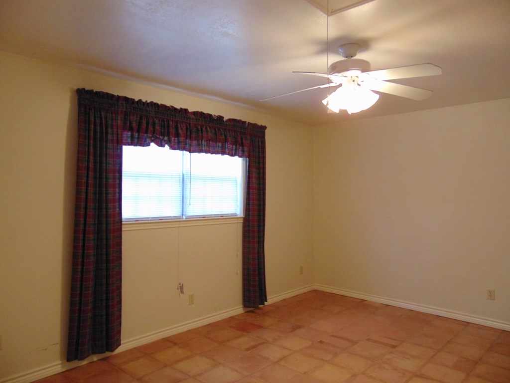 an empty living room with a ceiling fan and a window
