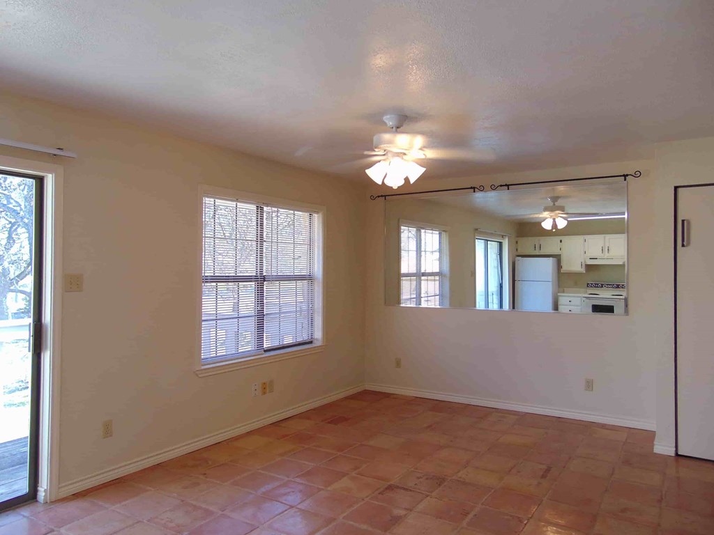 an empty living room with a sliding glass door to the kitchen