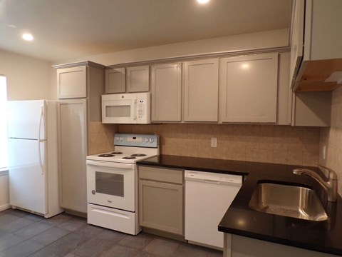 A kitchen with white appliances and brown countertops.