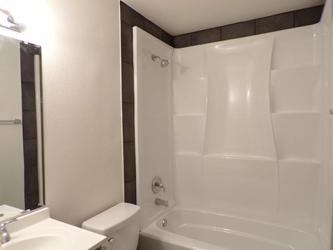 A white toilet sits next to a white sink in a small bathroom.