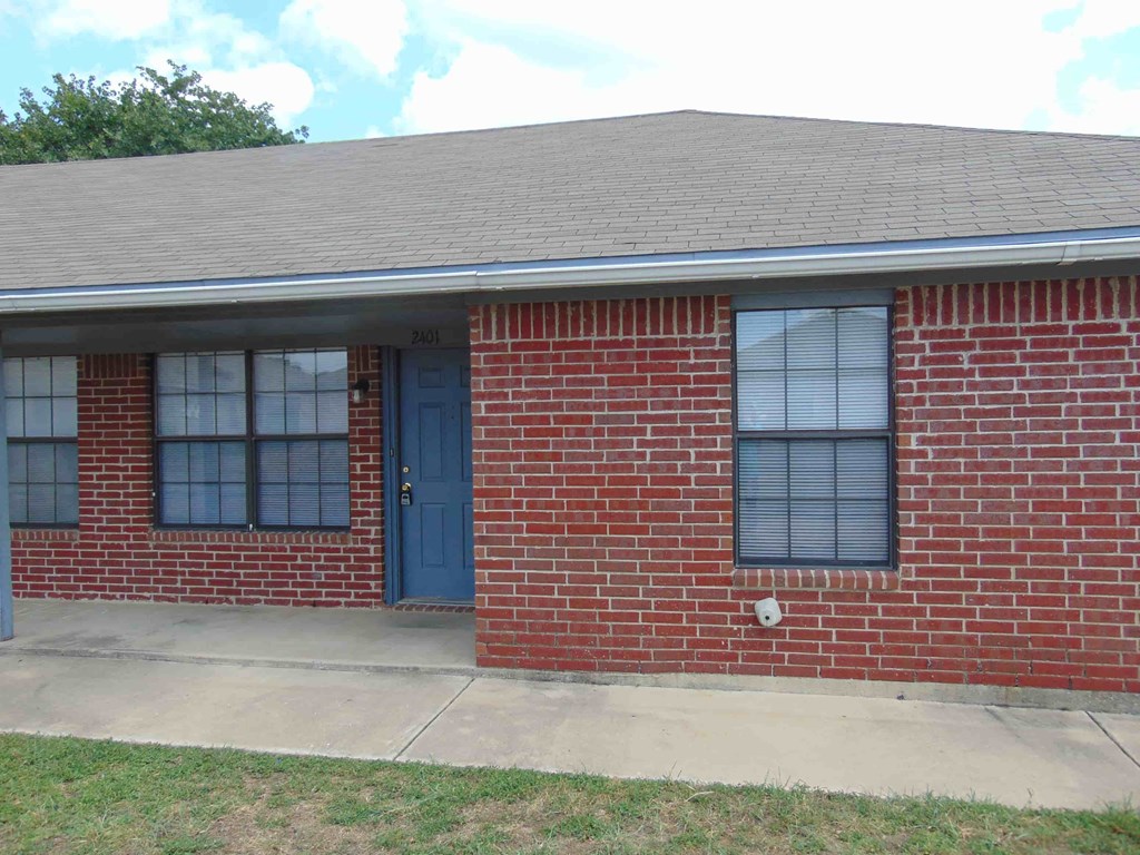 the front of a brick house with a blue door