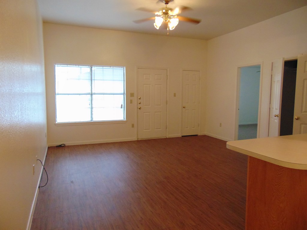 an empty living room with wood floors and a ceiling fan