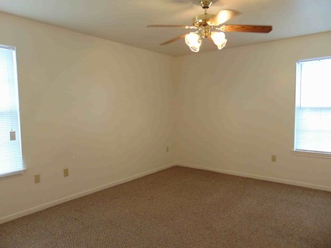 A room with a ceiling fan and carpeted floor.