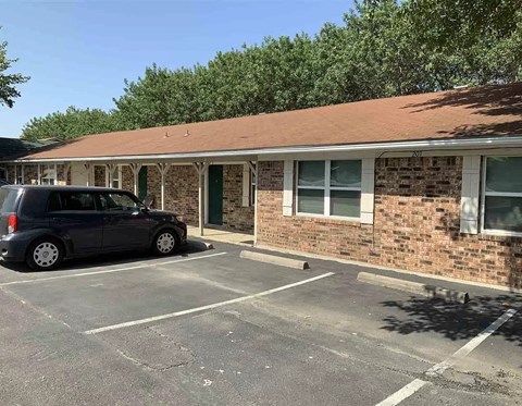 an empty parking lot in front of a brick building with a car parked