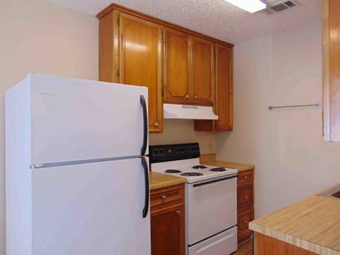 A white refrigerator stands in a kitchen with wooden cabinets.