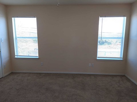 a living room with two windows and a carpet