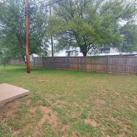 A backyard with a wooden fence and a grassy area.