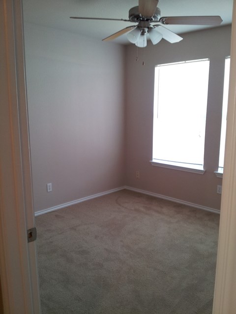 an empty room with a ceiling fan and a window