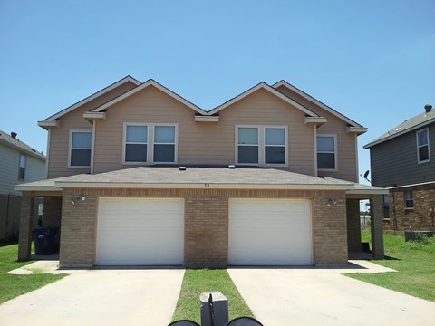 a tan house with two garage doors
