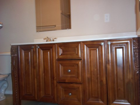 A wooden cabinet with a white counter top and a mirror above it.
