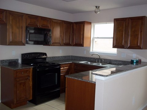 A kitchen with wooden cabinets and a black stove top oven.