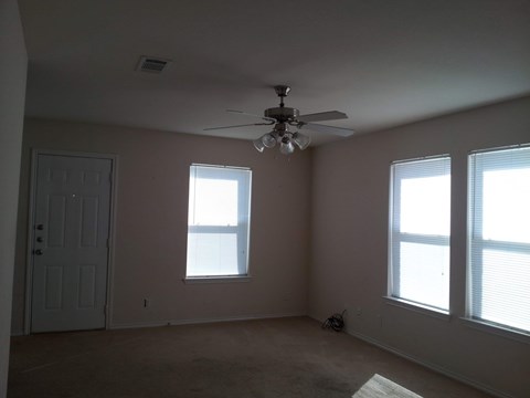 A room with a ceiling fan and two windows.