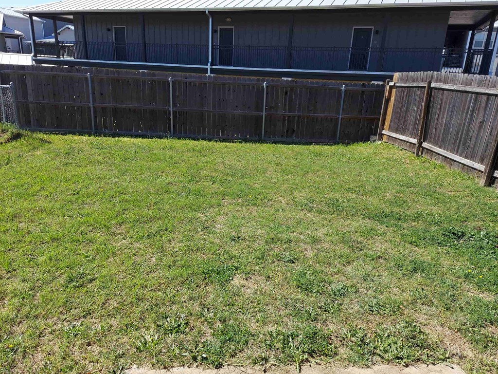 a yard with a fence and a house in the background