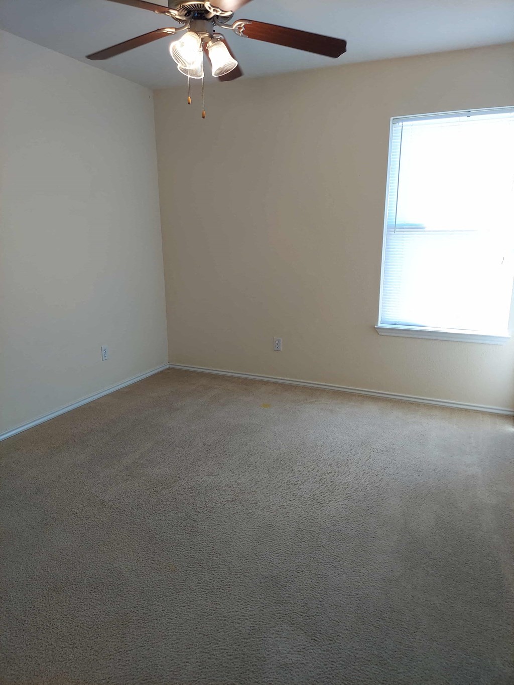 an empty living room with a ceiling fan and a window