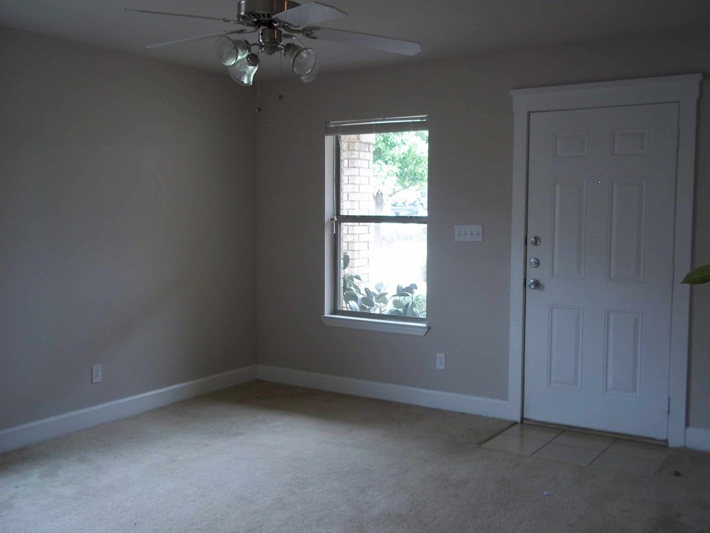 an empty room with a window and a ceiling fan