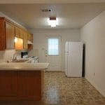 an empty kitchen with a sink and a refrigerator