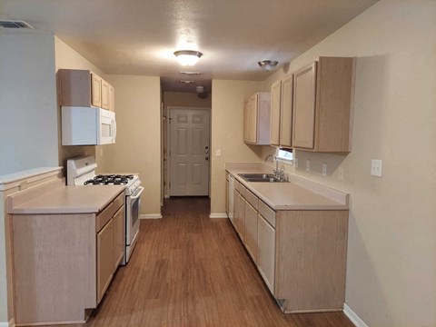 A kitchen with wooden cabinets and a white stove top oven.