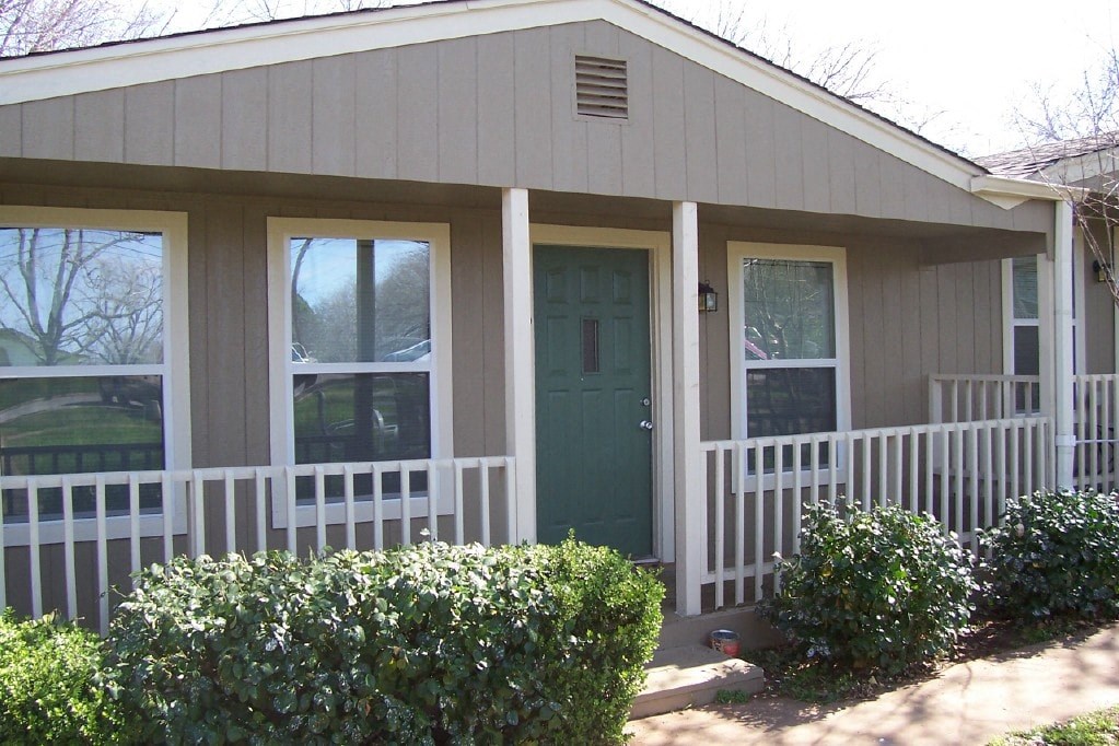 A small house with a green door and white fence.