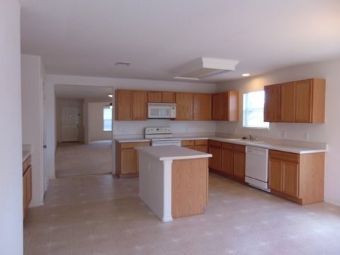 an empty kitchen with wooden cabinets and white appliances