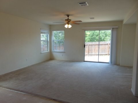 an empty living room with a ceiling fan