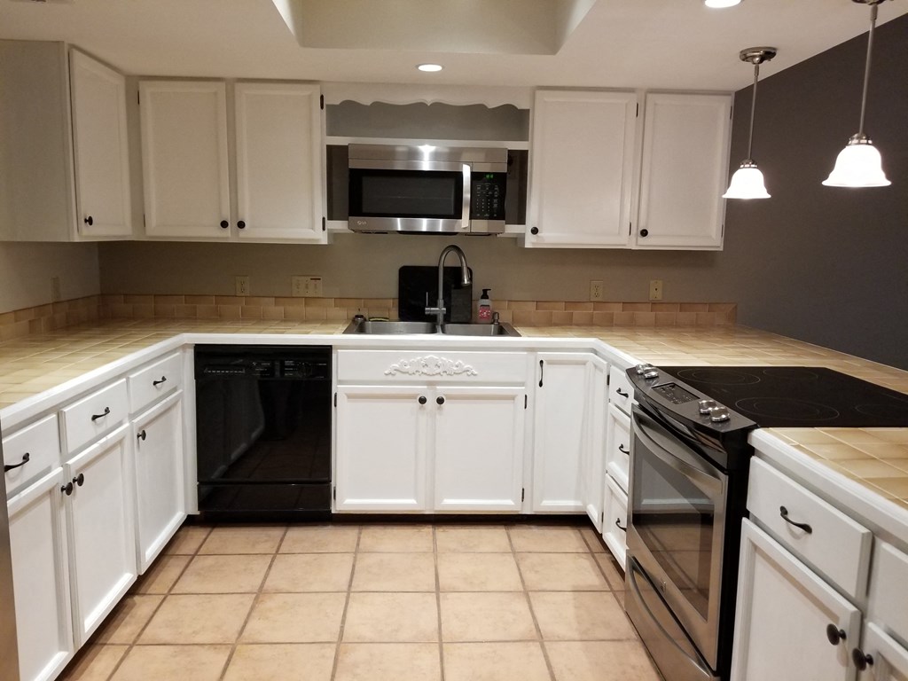 an empty kitchen with white cabinets and black appliances