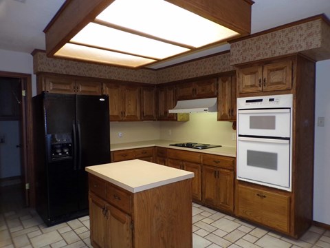A kitchen with wooden cabinets and a black refrigerator.