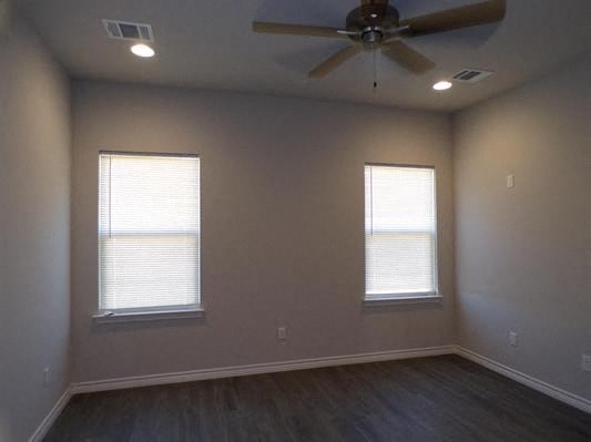 a empty room with a ceiling fan and two windows