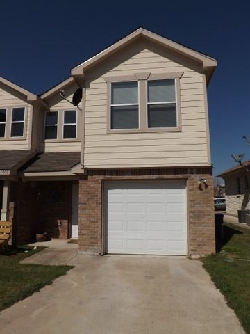 A house with a white garage door and a brick pillar.