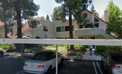 A white car is parked in a driveway in front of a house.