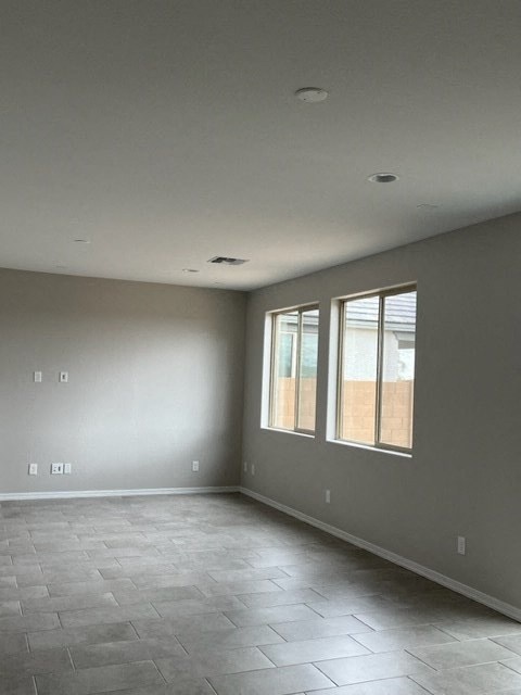 an empty living room with windows and a tiled floor