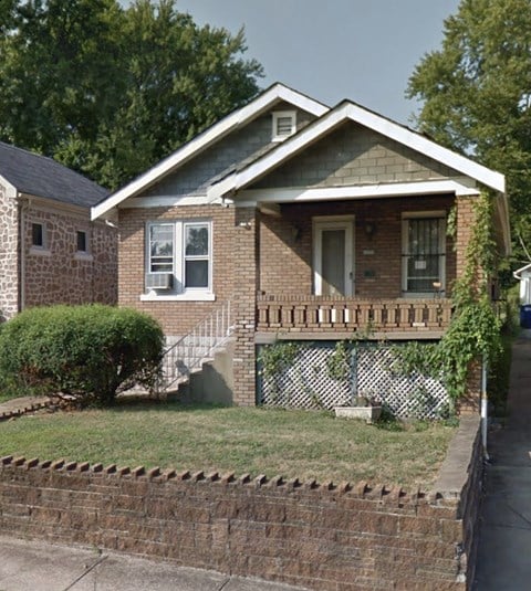 a brick house with a porch and a fence